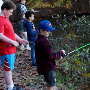 Scouts fishing beside a wooded stream